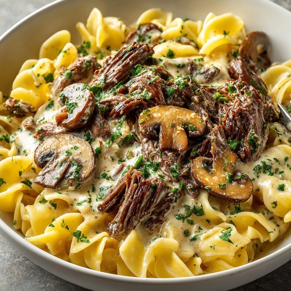 Creamy slow cooker beef stroganoff simmering, ready for serving over egg noodles.