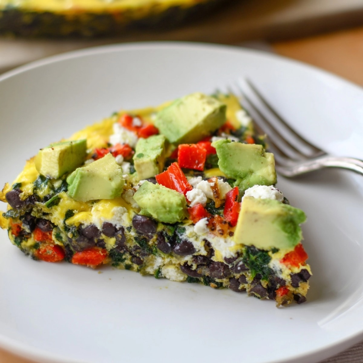 Top-down view reveals a golden Avocado Black Bean Egg Frittata, studded with colorful veggies.