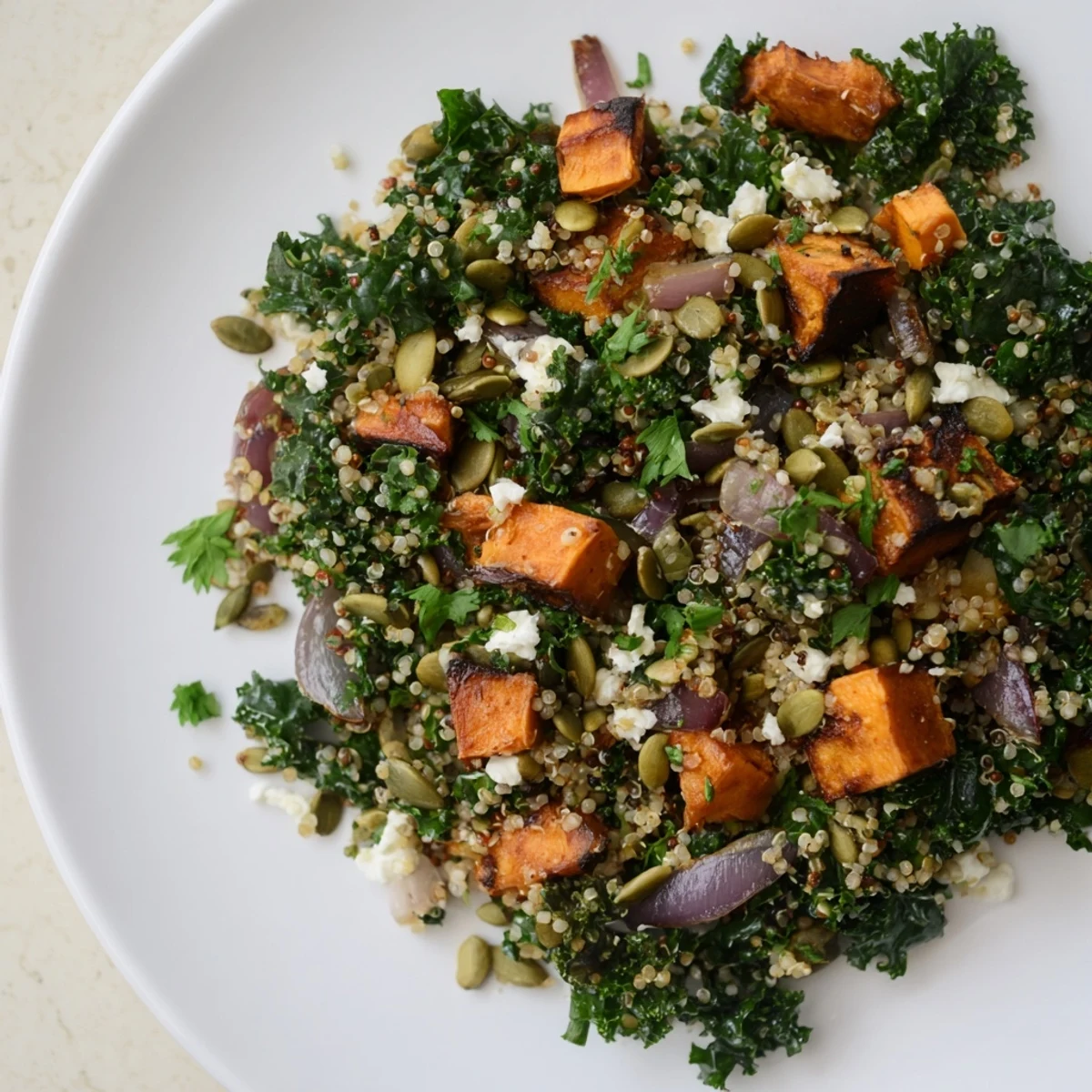 Golden roasted sweet potatoes nestled in a Kale & Quinoa Salad, drizzled with tangy dressing, ready to enjoy.