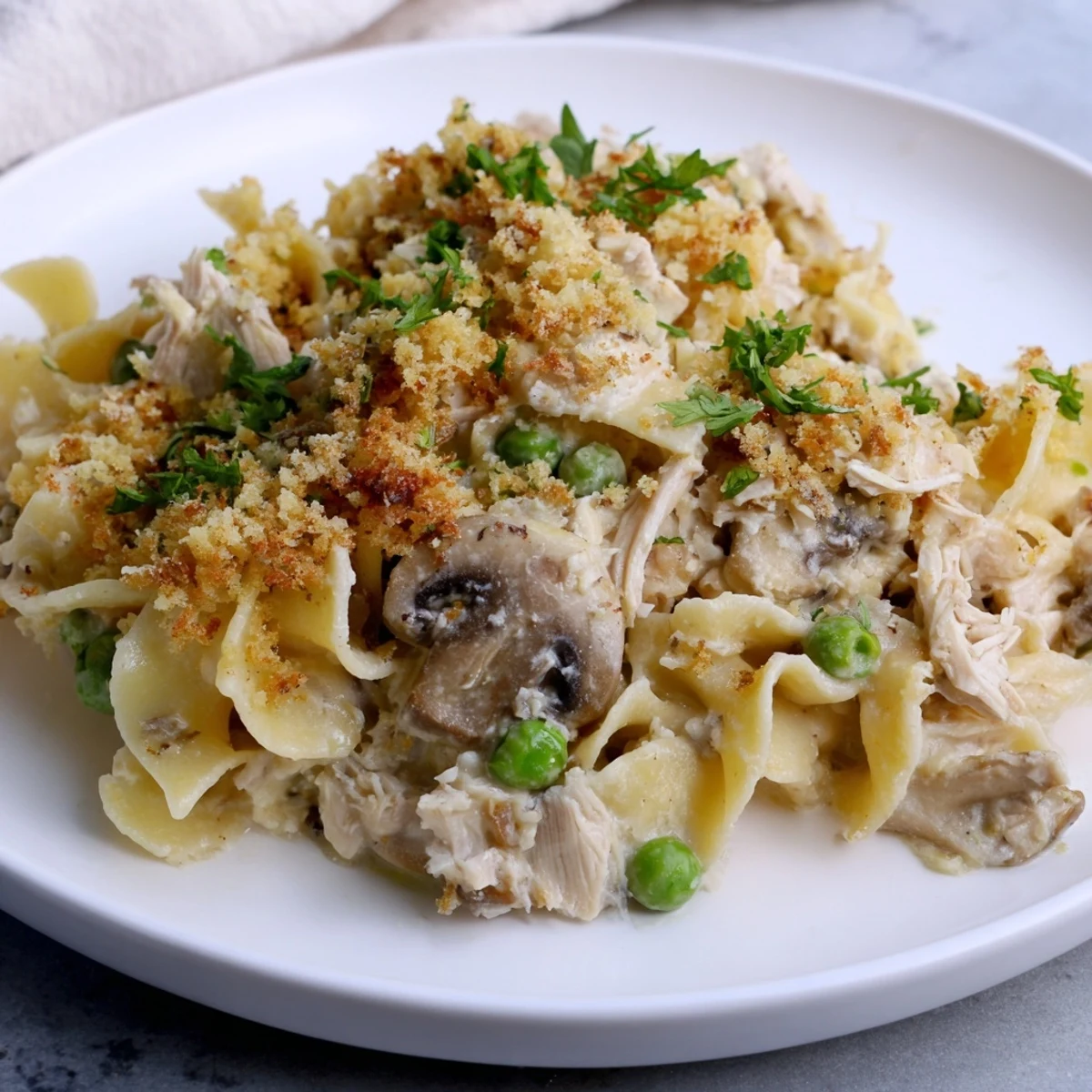 Golden, bubbly Tuna Noodle Casserole 2.0 with a crispy topping, ready for serving alongside fresh parsley.