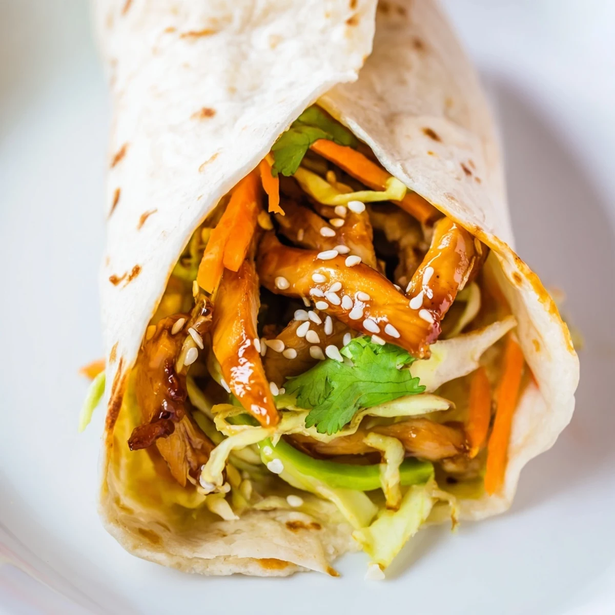 A warm teriyaki chicken wrap on a wooden board with extra sauce drizzled over the top.