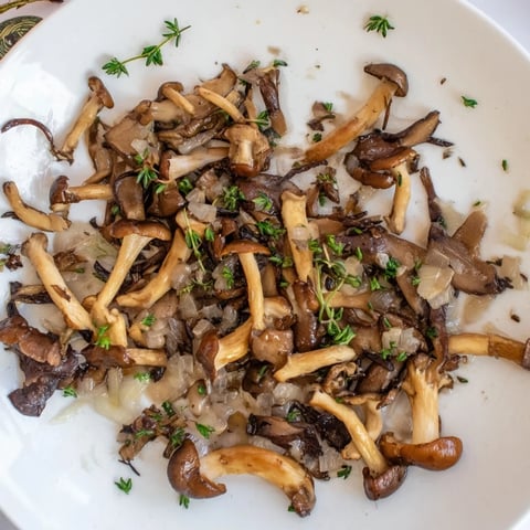 Golden wild mushrooms, the Enchanted Forest Mushrooms, sizzling in a pan with garlic and herbs, ready to serve.