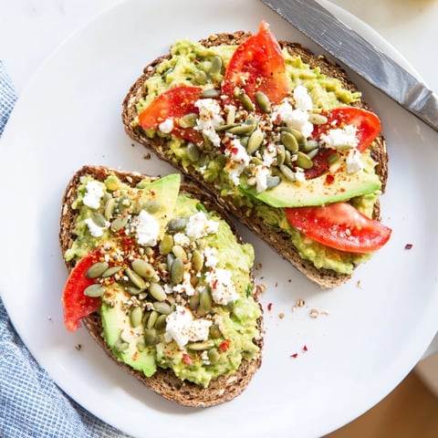 Creamy avocado mash seasoned with lemon, salt, and pepper on crispy whole grain toast for a quick vegetarian breakfast.