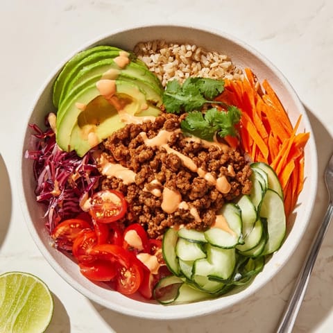 Delicious plant-based meat bowl garnished with creamy avocado and zesty lime wedges.  