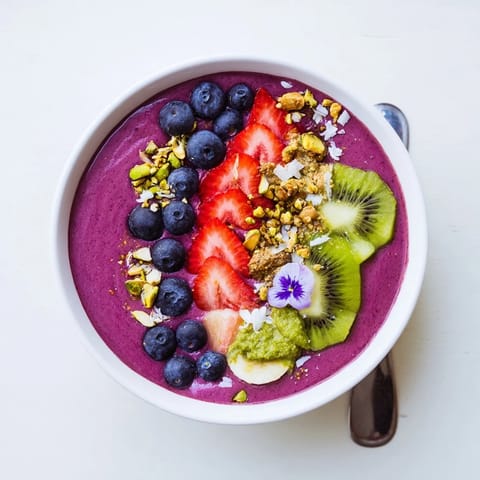 A colorful breakfast of smoothie bowls with kiwi, berries, and crunchy toppings.  