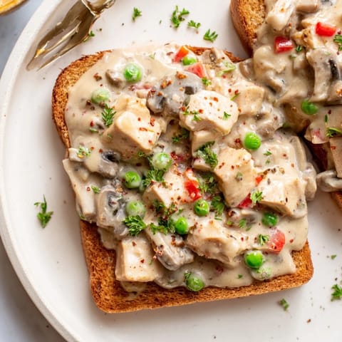 Warm Chicken à la King, a decadent photo of the sauce cascading over buttered toast ready to plate.