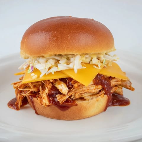 Warm, saucy BBQ Chicken Sliders garnished with coleslaw, ready to be enjoyed with friends or family.