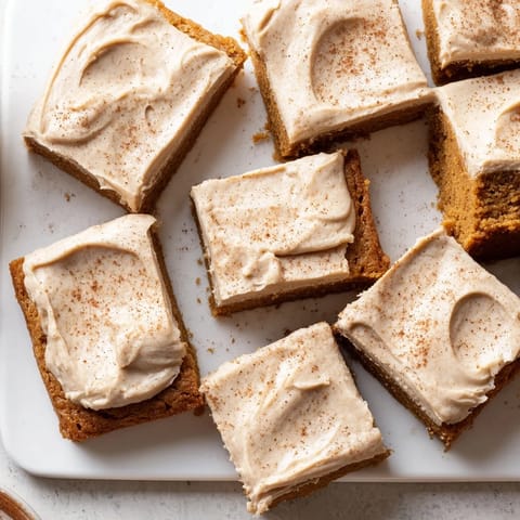 A close-up of frosted pumpkin bars, showing the creamy texture of the brown sugar frosting.
