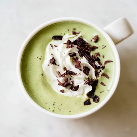 A frothy Collagen Peppermint Mocha Matcha Latte, picture a creamy, rich drink with optional whipped cream topping.