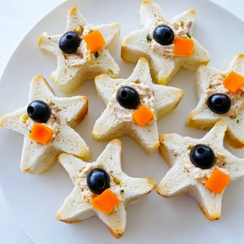 A platter of Mini Starfish Sandwiches, ready to serve with olives and capers for a fun party snack.