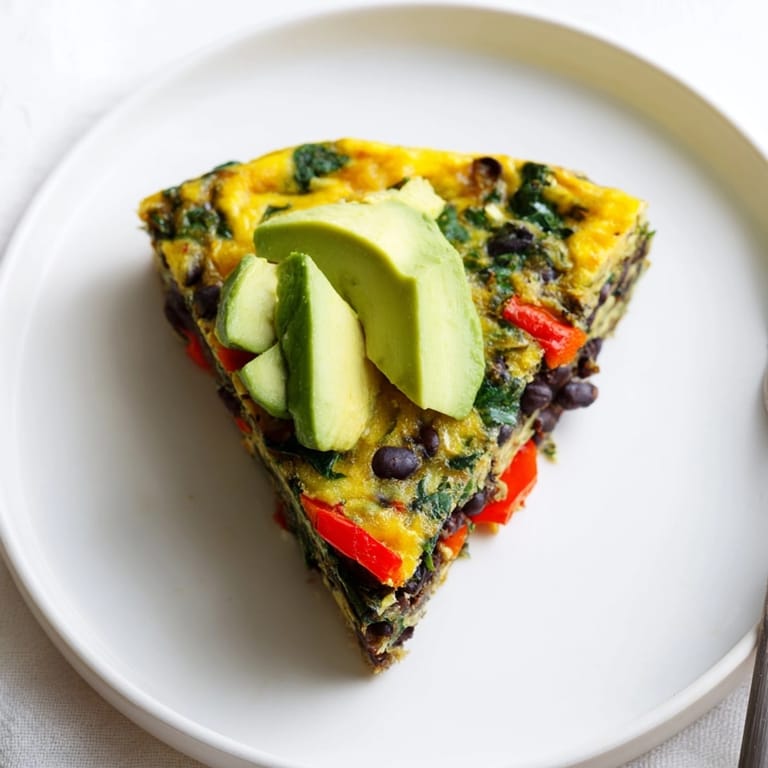 Close-up shows savory Avocado Black Bean Egg Frittata with creamy avocado and melted feta.