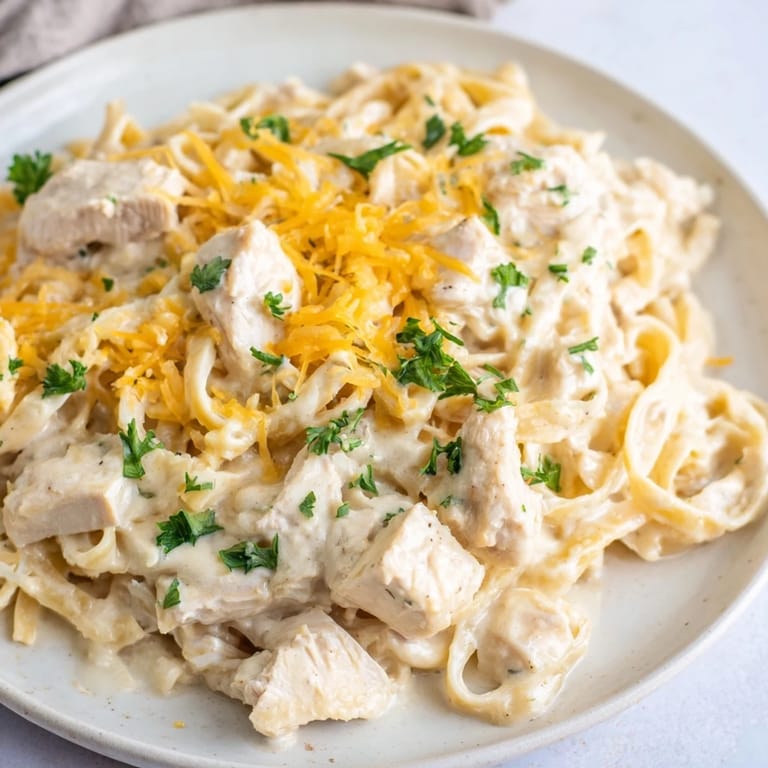 A close-up of creamy Chicken Fettuccine Alfredo Bake, topped with melted mozzarella and Parmesan cheese for dinner.