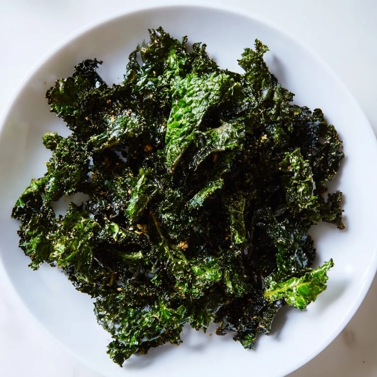 Homemade baked kale chips, fresh from the oven, offering a savory, crunchy texture.