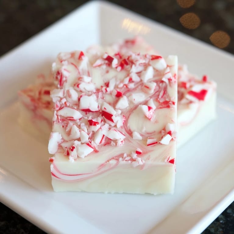 Festive, homemade white chocolate peppermint bark fudge bars, perfect for holiday gifting with vibrant peppermint flecks.