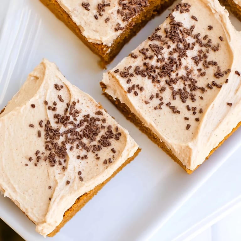 Perfect squares of homemade pumpkin bars, a spiced autumn dessert, frosted lavishly.