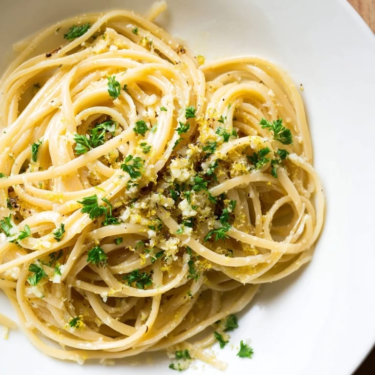 Creamy Garlic Butter Linguine, a simple Italian delight, garnished with Parmesan and lemon.