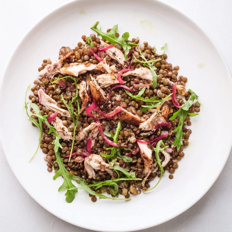 A close-up view of a colorful Lentil & Chicken Spring Salad featuring juicy cherry tomatoes and crisp cucumber slices on a rustic wooden table.  